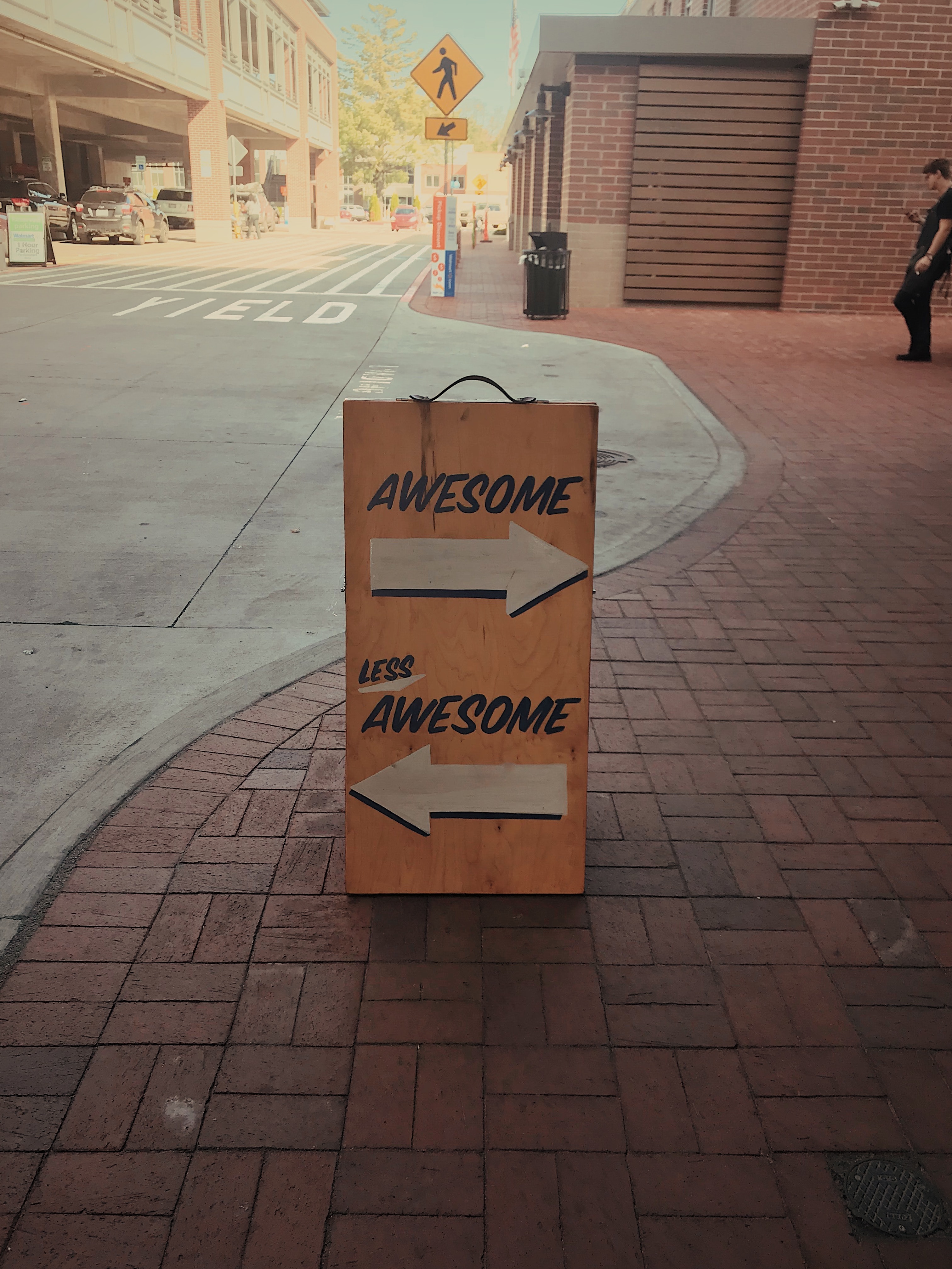 A sign on a street that says "awesome" and "less awesome"