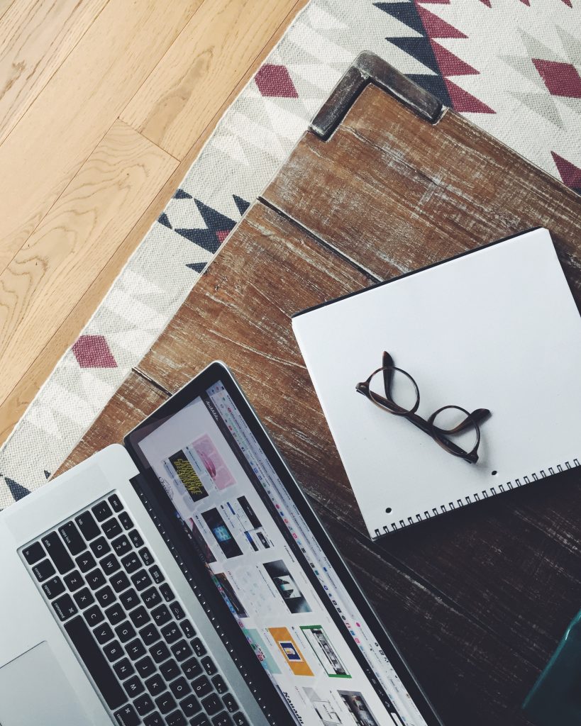 laptop with open notebook and glasses